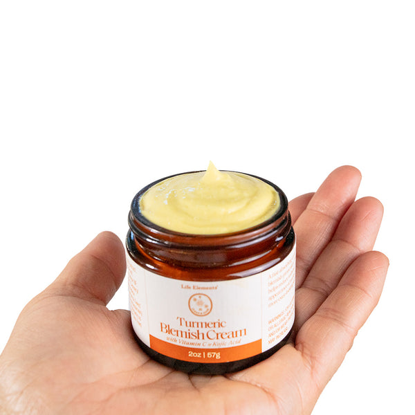 Hand holding a jar of Turmeric Blemish cream from Life Elements
